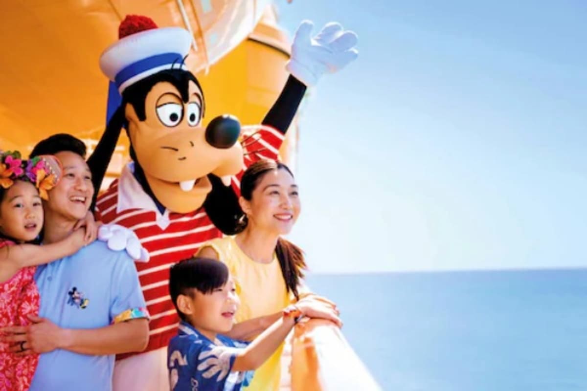 Family with children posing next to cartoon sailor character mascot with ocean and sky background