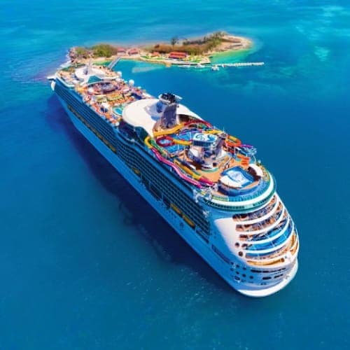 Aerial view of large cruise ship docked at tropical island resort with turquoise water and sandy beach