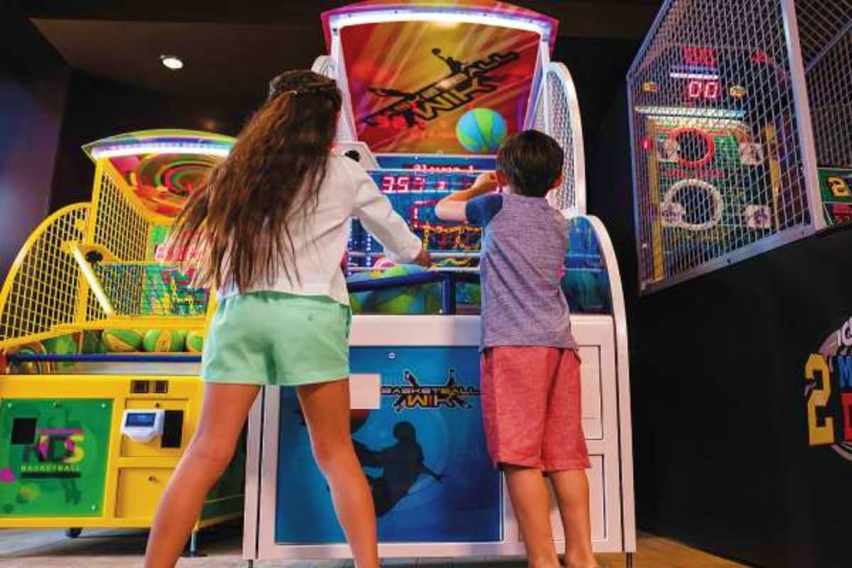 Children playing interactive arcade basketball games in an indoor entertainment center