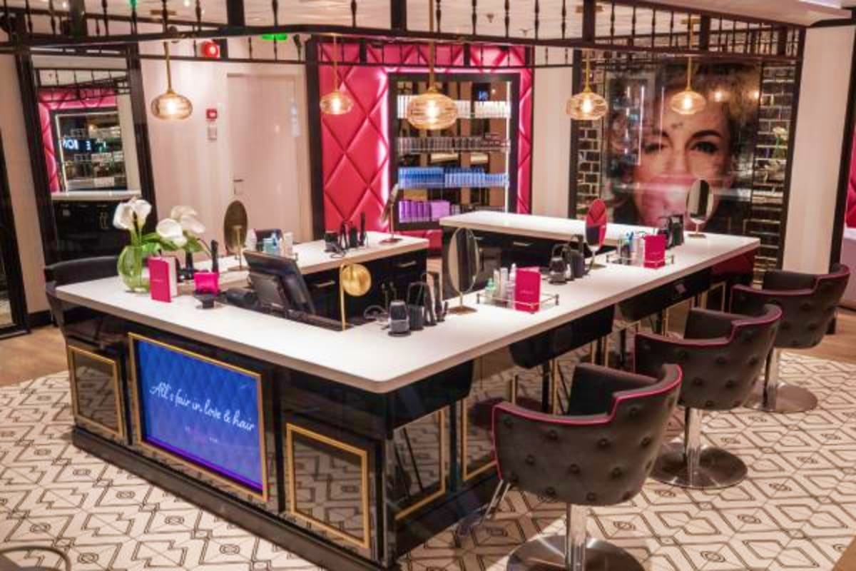 Modern luxury hair salon interior with pink and black design, white countertops, pendant lighting, and professional styling s
