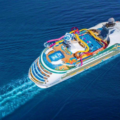 Aerial view of large cruise ship with colorful waterslides and entertainment deck in deep blue ocean waters