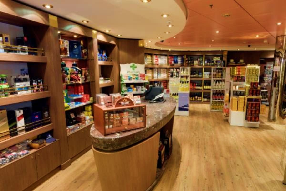 Modern retail pharmacy interior with curved wooden counter, shelving displays of medications and health products, recessed li