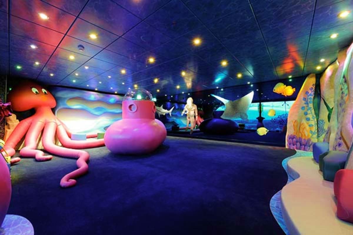 Colorful underwater-themed children's play area with red octopus, pink submarine, and coral reef scenery on cruise ship