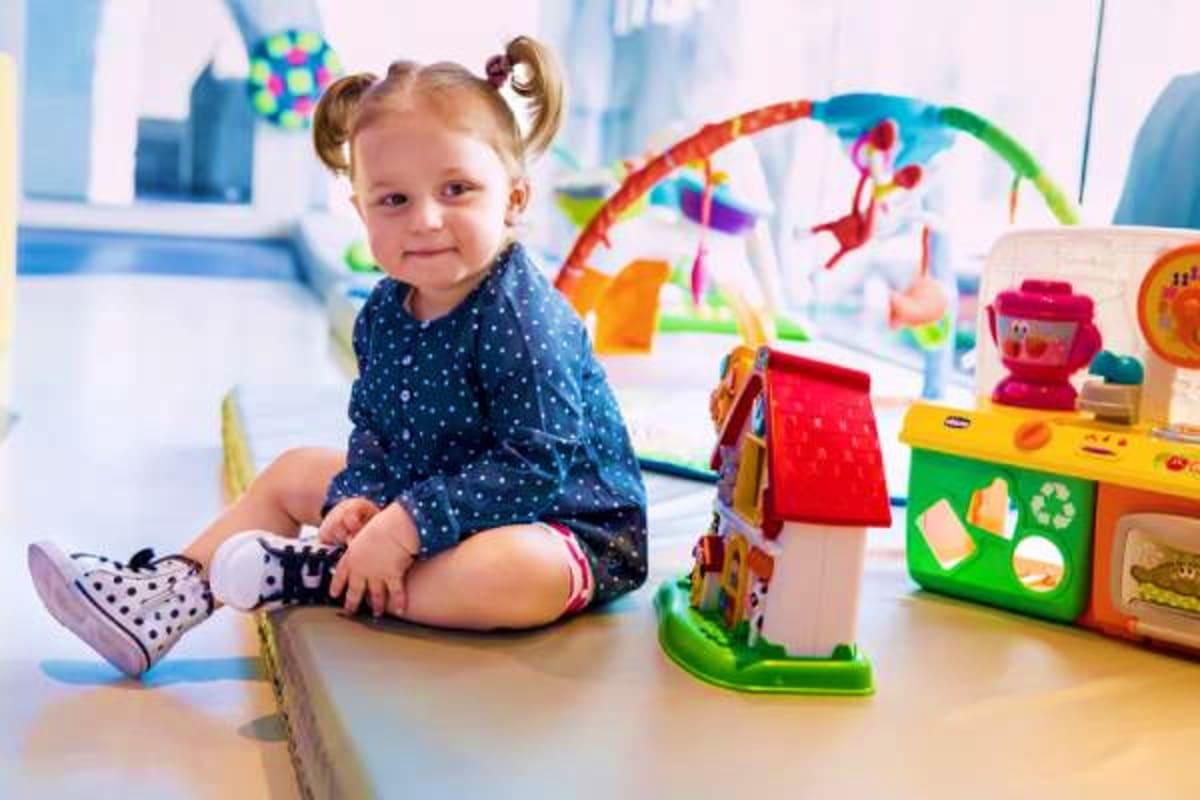 Toddler playing with colorful educational toys and activity gym in bright playroom setting