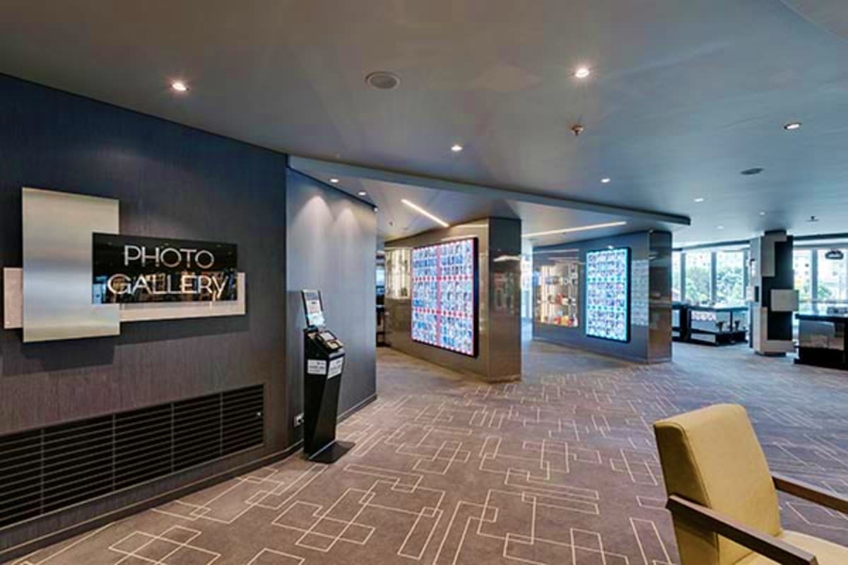Modern photo gallery entrance in cruise ship corridor with illuminated signage and digital displays