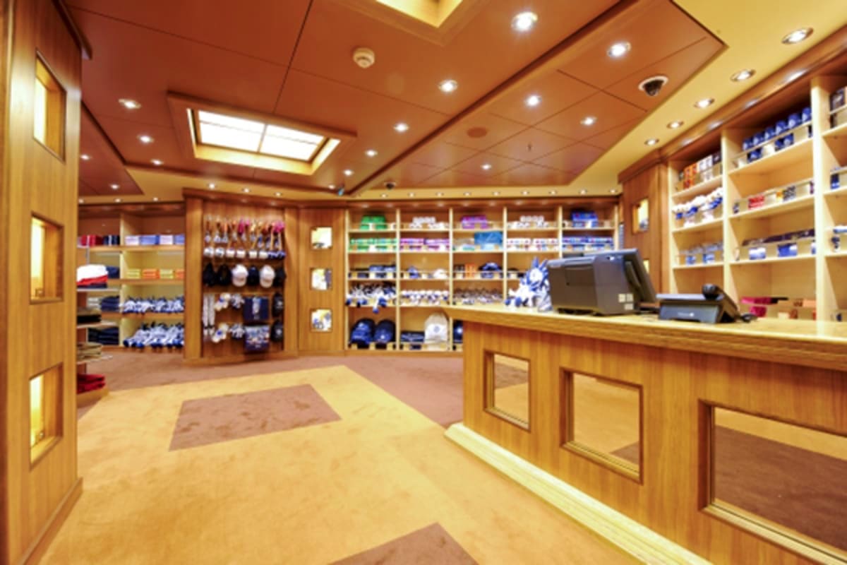 Luxury ship boutique interior with wooden cabinetry, shelving displays, checkout counter, and recessed ceiling lighting