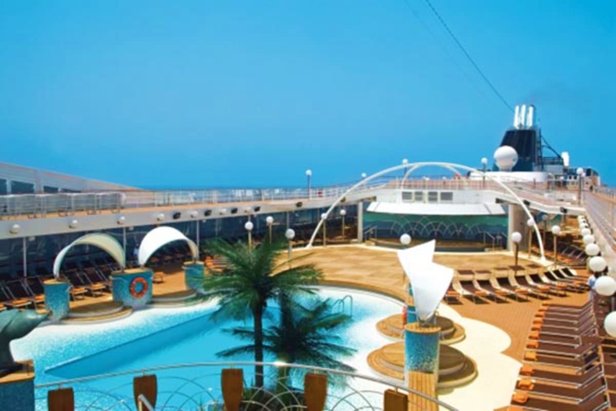 MSC Magnifica cruise ship deck with swimming pool, lounge chairs, palm tree, and architectural structures under clear blue sk