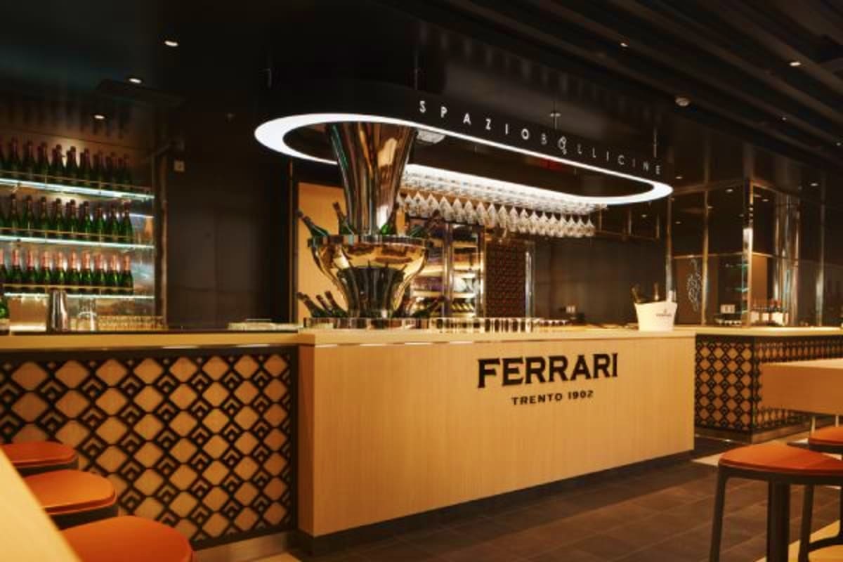 Ferrari Trento 1902 wine bar counter with modern lighting and orange seating in upscale restaurant interior