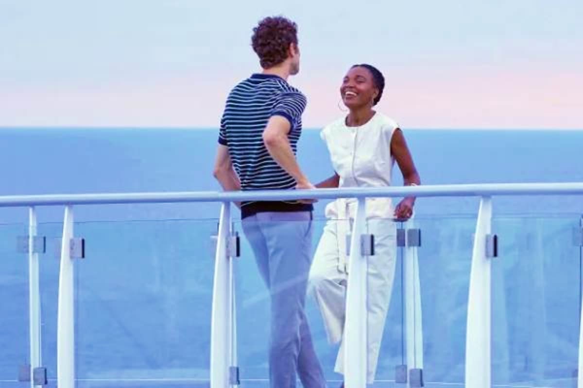 Two people enjoying conversation on a cruise ship deck railing overlooking the ocean