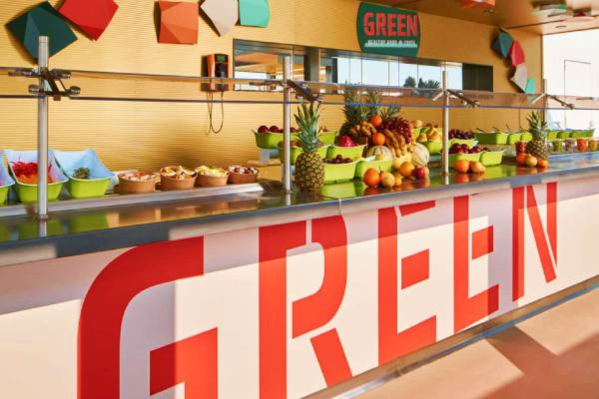 Fresh produce display at farmer's market stand with colorful fruits and vegetables in green bowls and baskets
