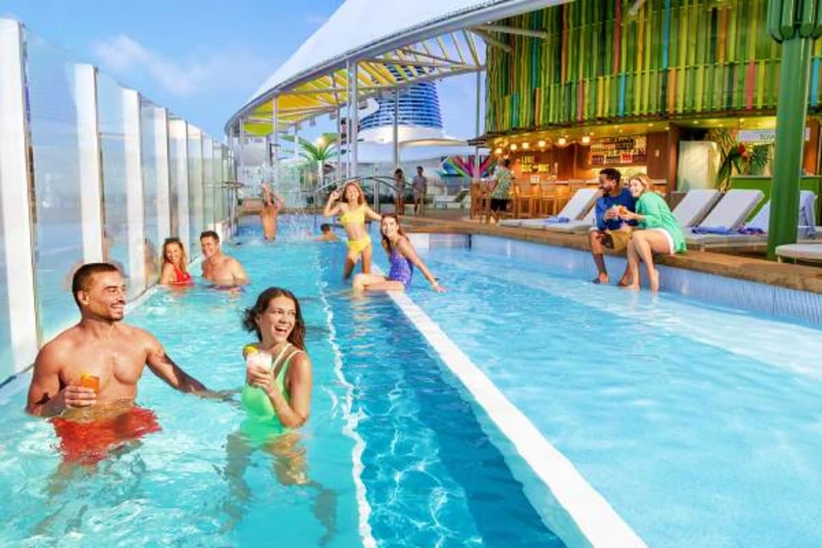 Families and couples enjoying an indoor swimming pool with ocean views aboard Legend of the Seas cruise ship