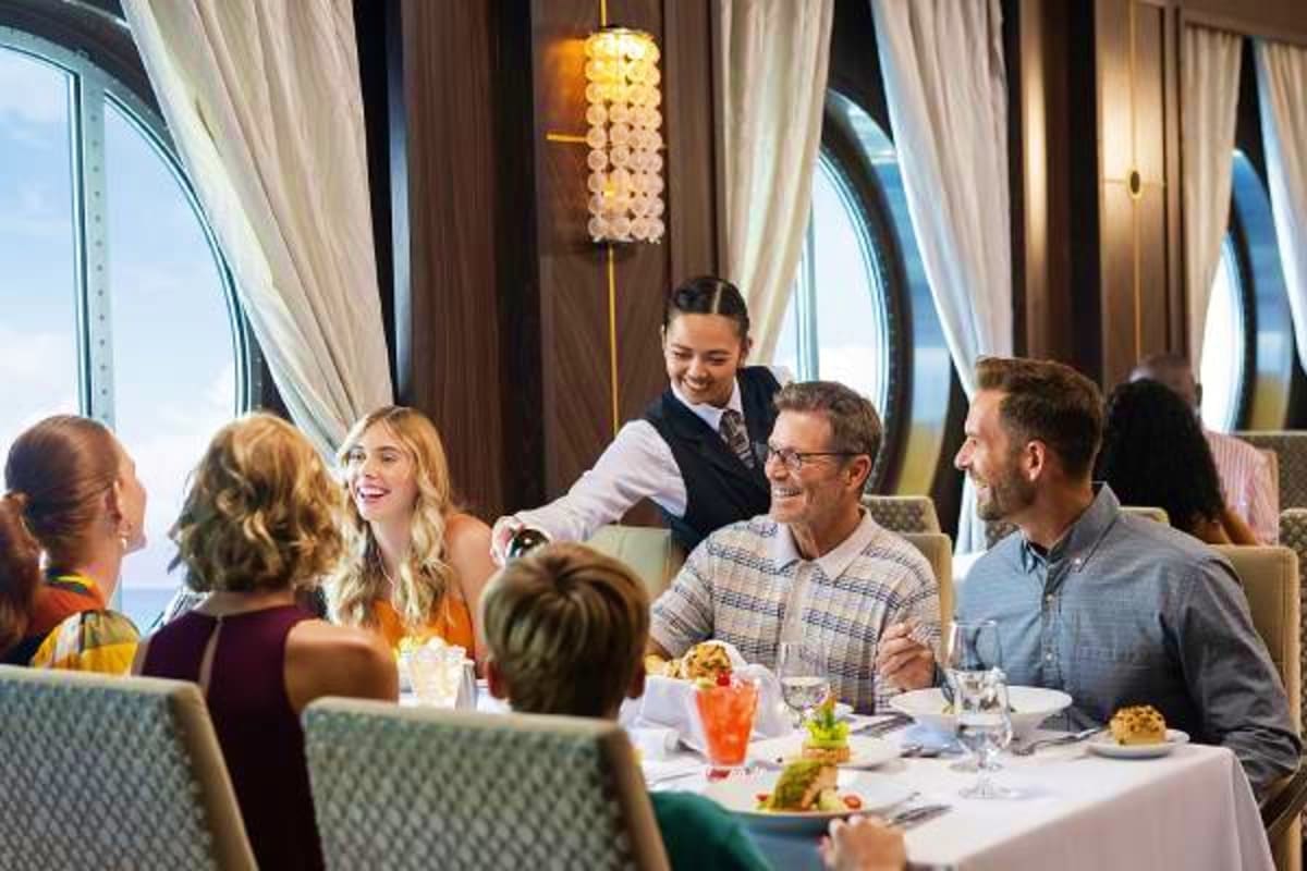 Passengers dining at an upscale restaurant aboard Legend of the Seas with ocean views and elegant decor