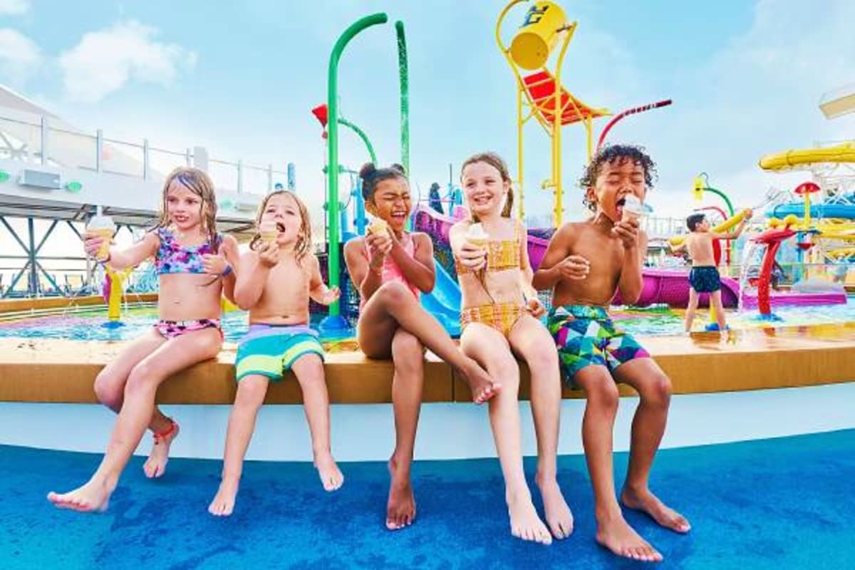 Group of children eating ice cream at a water park with colorful slides and attractions on a cruise ship
