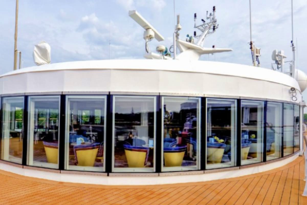 Arctic Wonders of Greenland and Iceland Modern cruise ship deck with curved glass windows, yellow lounge chairs, communication antennas, and ocean view on horizon