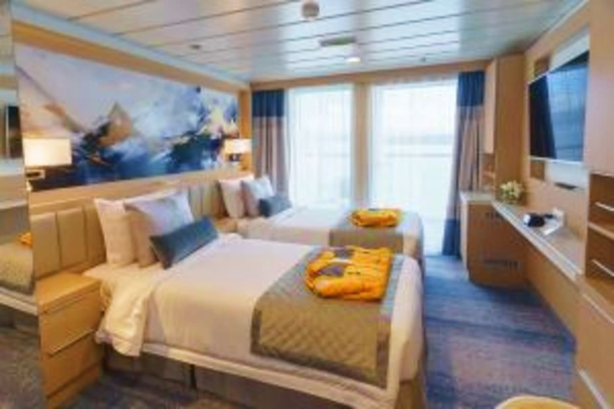 Greenland’s High Arctic Odyssey Luxury cruise ship cabin with twin beds, ocean view windows, wooden furnishings, and modern décor in warm tones