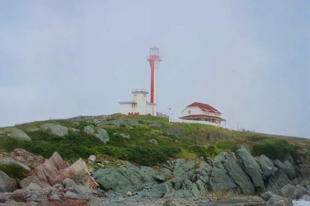 Greenland’s High Arctic Odyssey Red and white striped lighthouse on rocky coastal headland with keeper's house, Greenland Arctic landscape