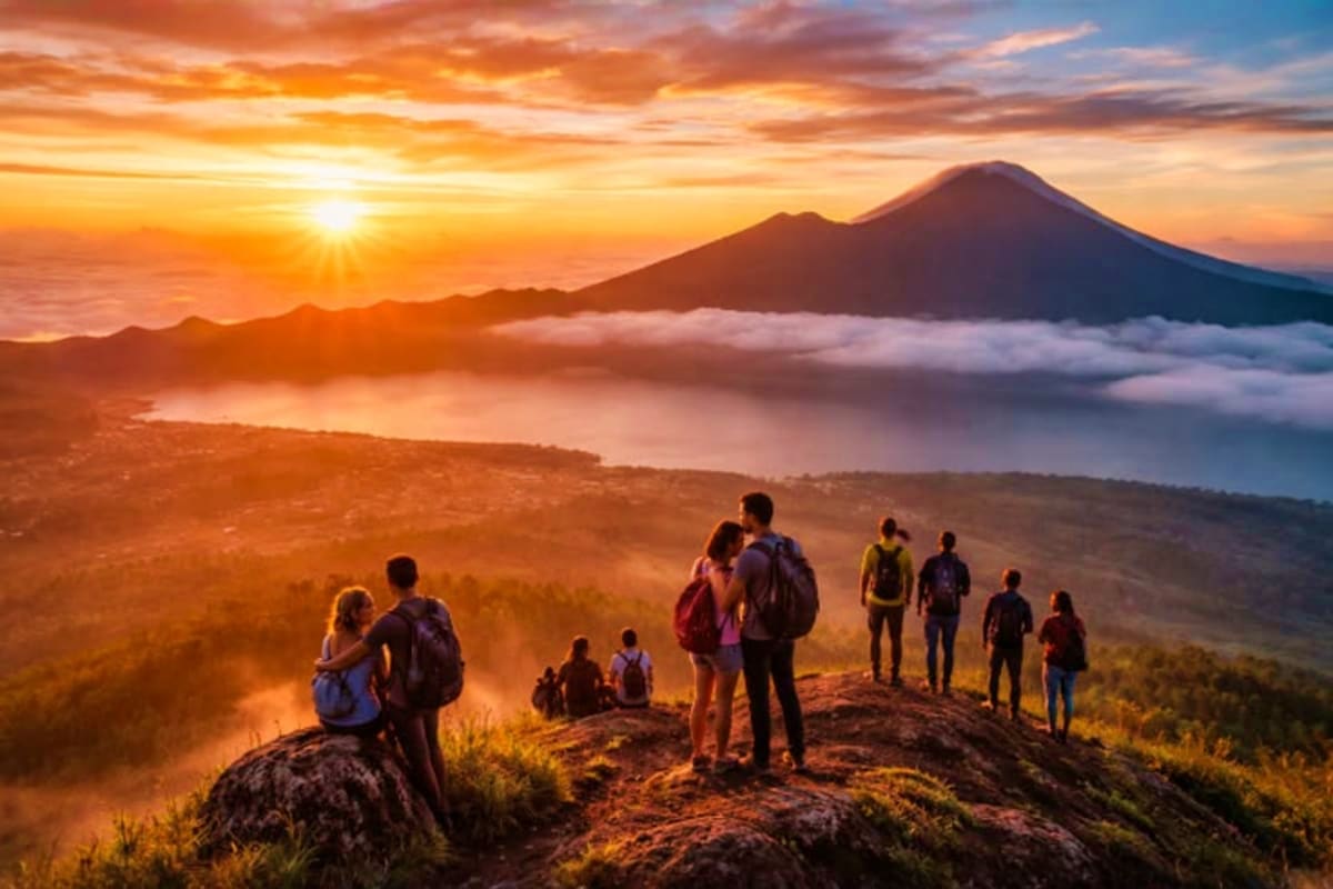 Group of hikers watching sunrise over Mount Agung volcano in Bali with clouds and valley below