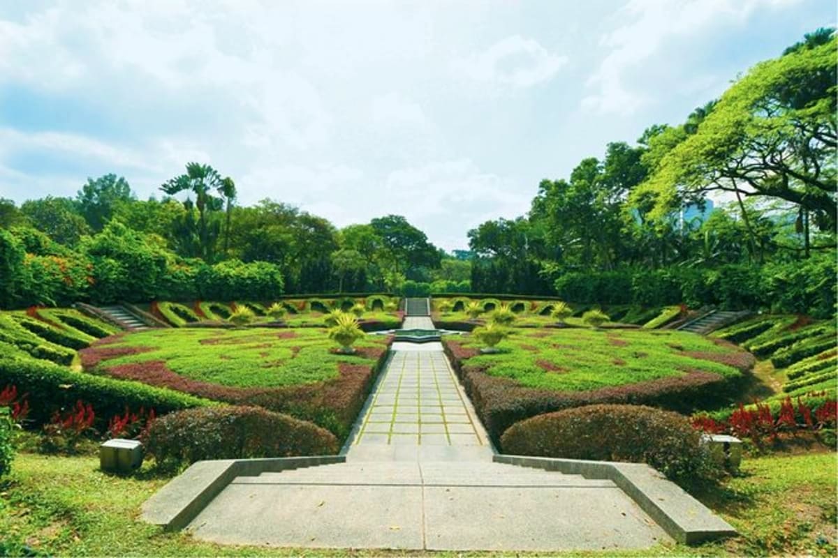 Malaysia Honeymoon Symmetrical formal garden with straight paved pathway leading through manicured hedges and lush tropical vegetation in Malays