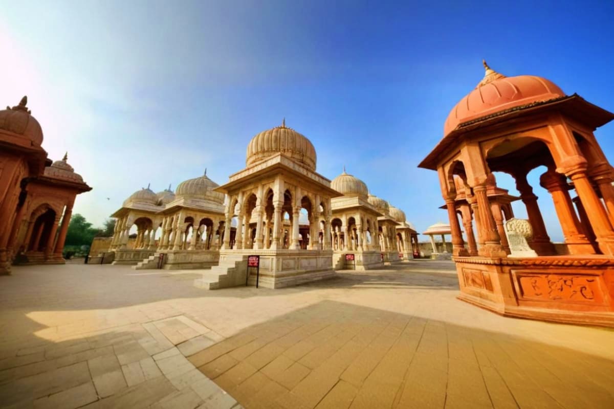 Historic sandstone temples with ornate domes and pavilions in Rajasthan under clear blue sky