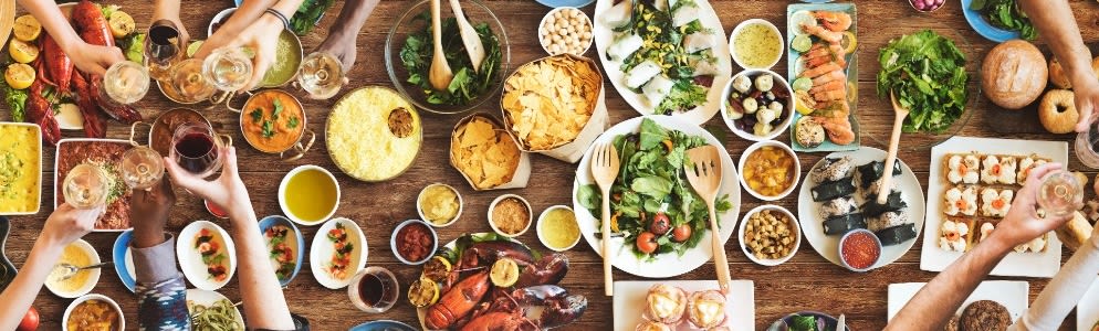 Fællesbord med vin og mad – forskellige retter og vinglas omkring langbord