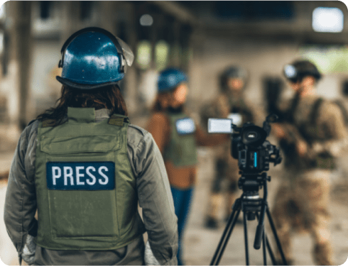 Photojournalist carrying camera equipment while reporting in a hostile environment