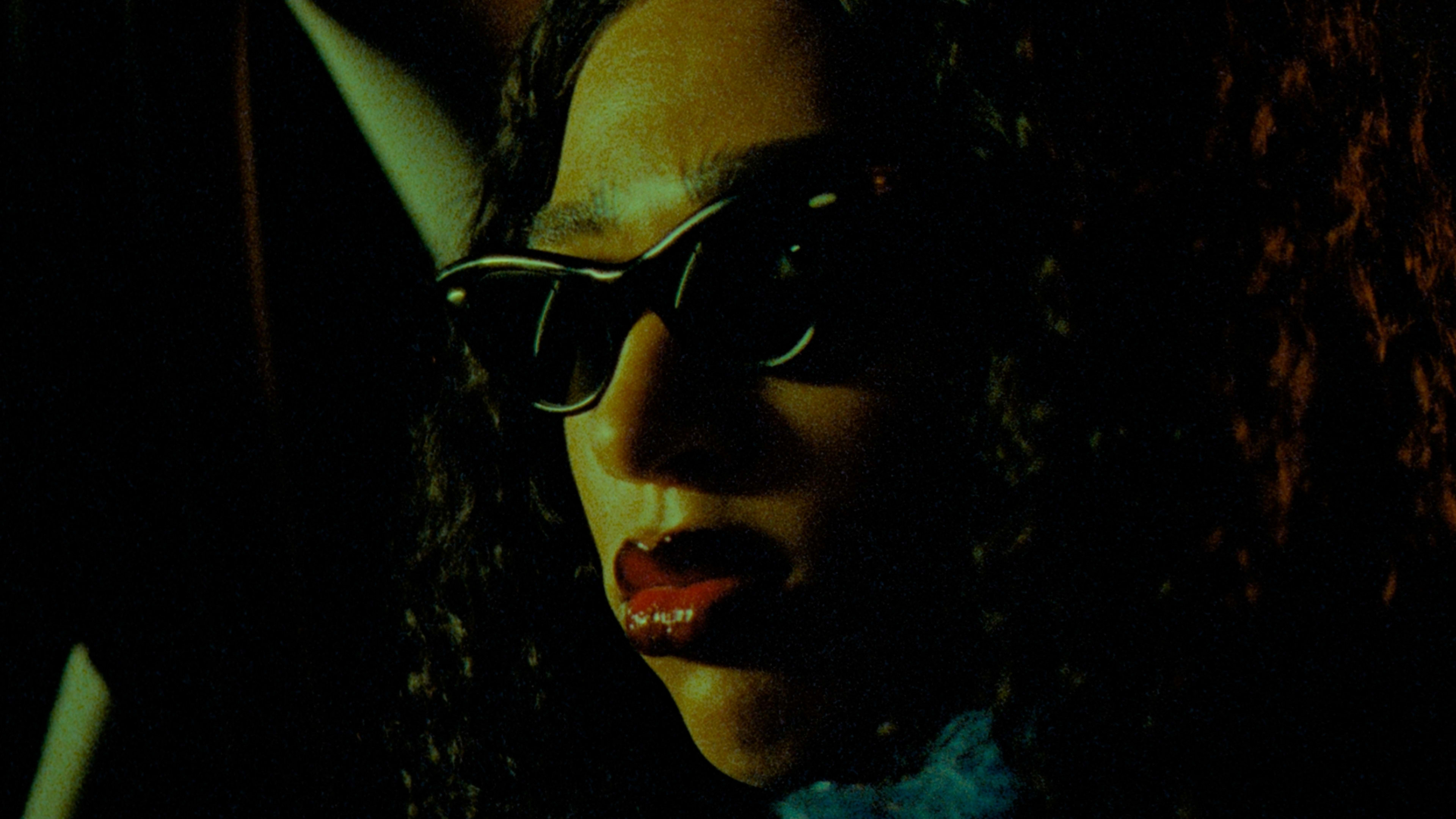 Mystisches Porträt mit Sonnenbrille, intensives color-grading, gelb-orange Haut, rote Lippen.