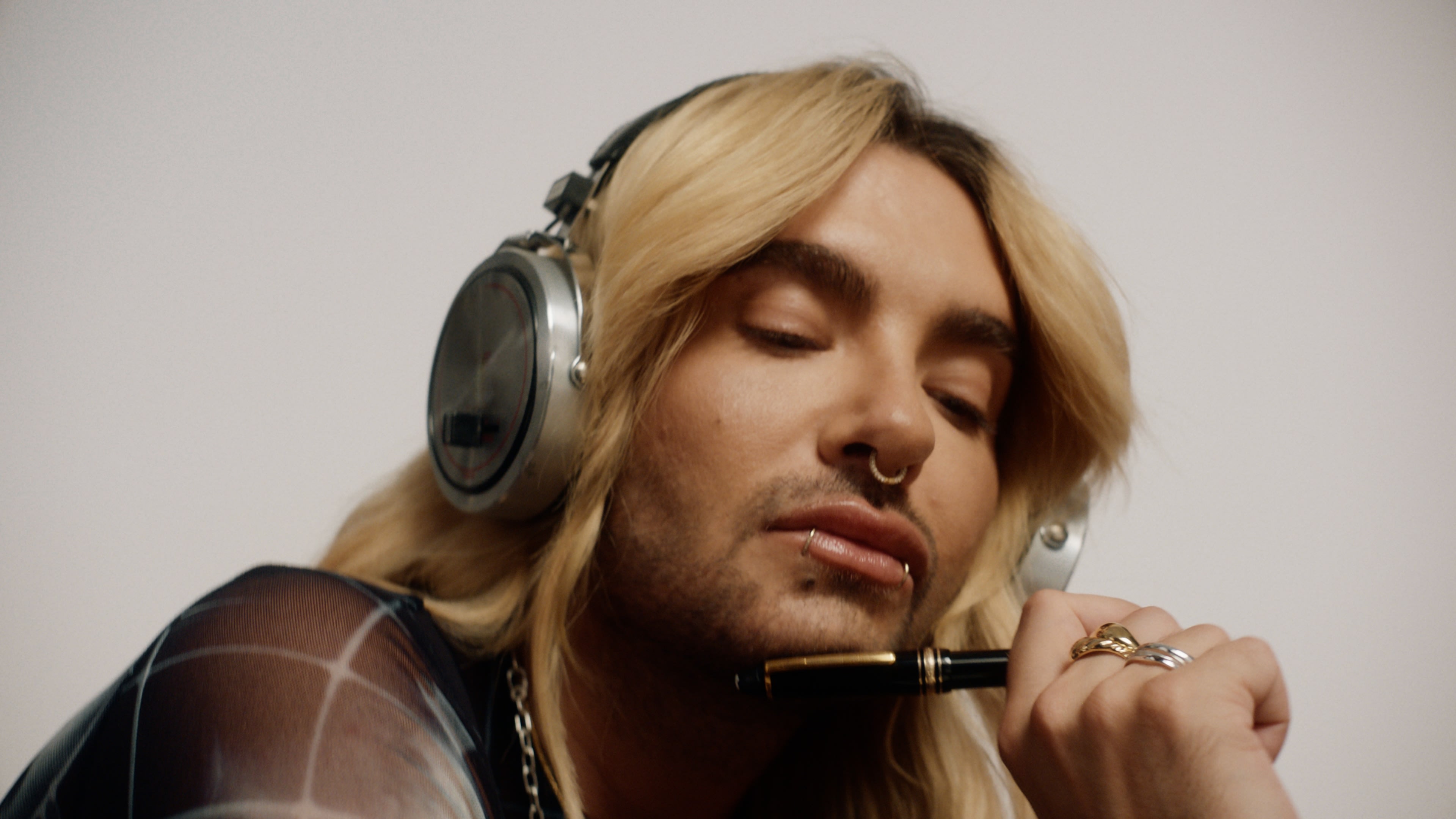 Kontemplatives Porträt mit Bill Kaulitz, Kopfhörer und Stift. Professionelles Color-Grading für ruhige Ausstrahlung.