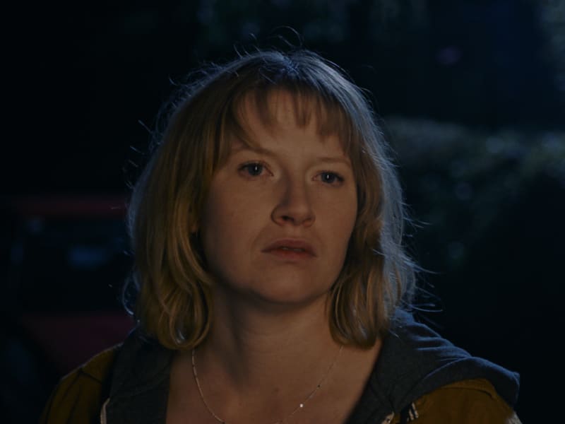 Colorist mit digitalem Grading: Dunkle Stimmung, warme Töne, Frau im Abendlicht.