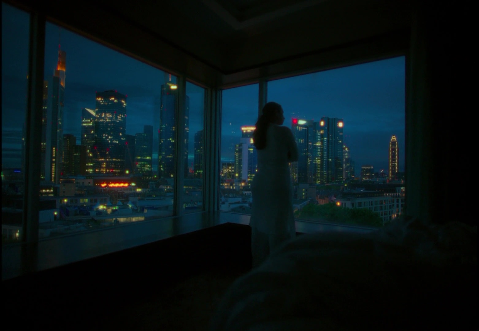 Stimmungsvolles Color Grading einer Frau vor beleuchteter Skyline im Nachtblau.