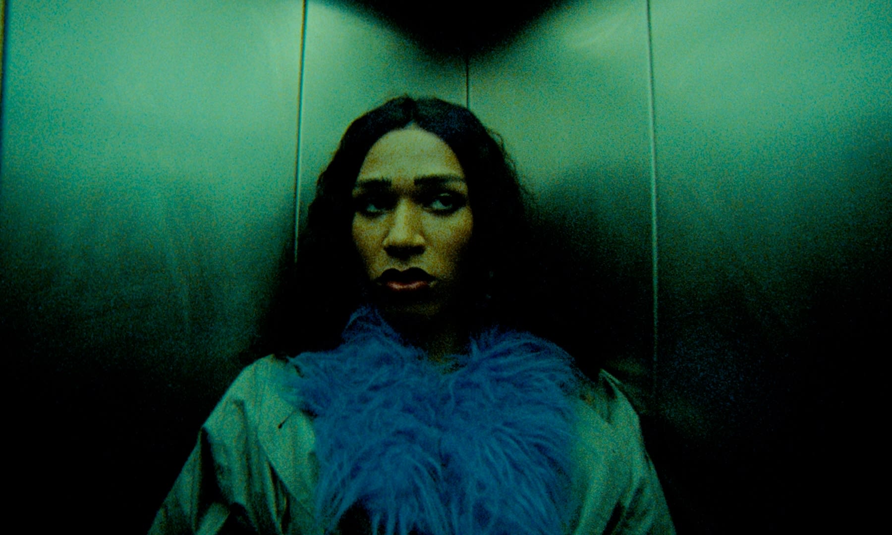 Intensives Color-Grading: Person im teal-grünen Lift, blauer Schal, dramatische Stimmung.