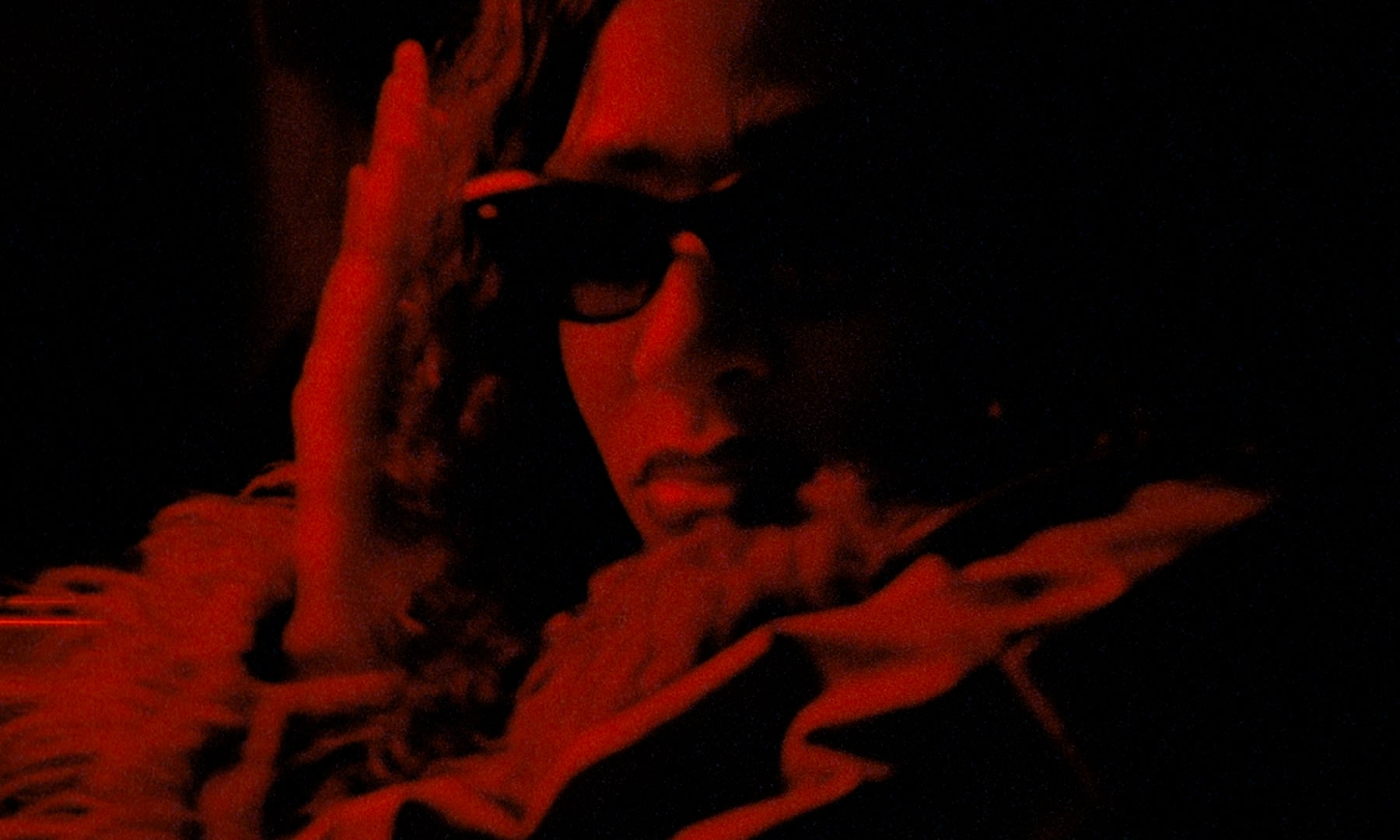 Stimmungsvolles color-grading: Frau mit Sonnenbrille in tiefrotem Licht, künstlerisch und intensiv.