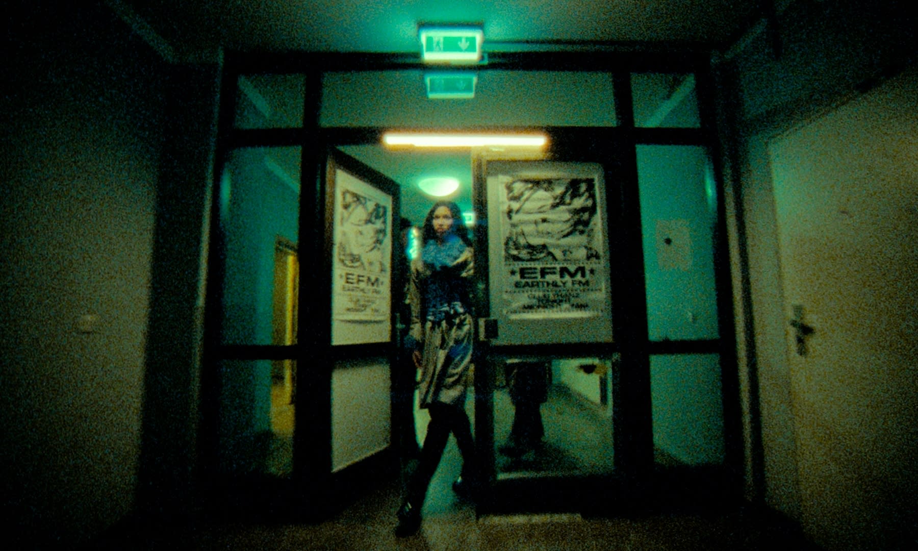 Atmosphärisches Color-Grading: Frau in türkis-grünem Flur, warmes Licht, körniger Retro-Look.