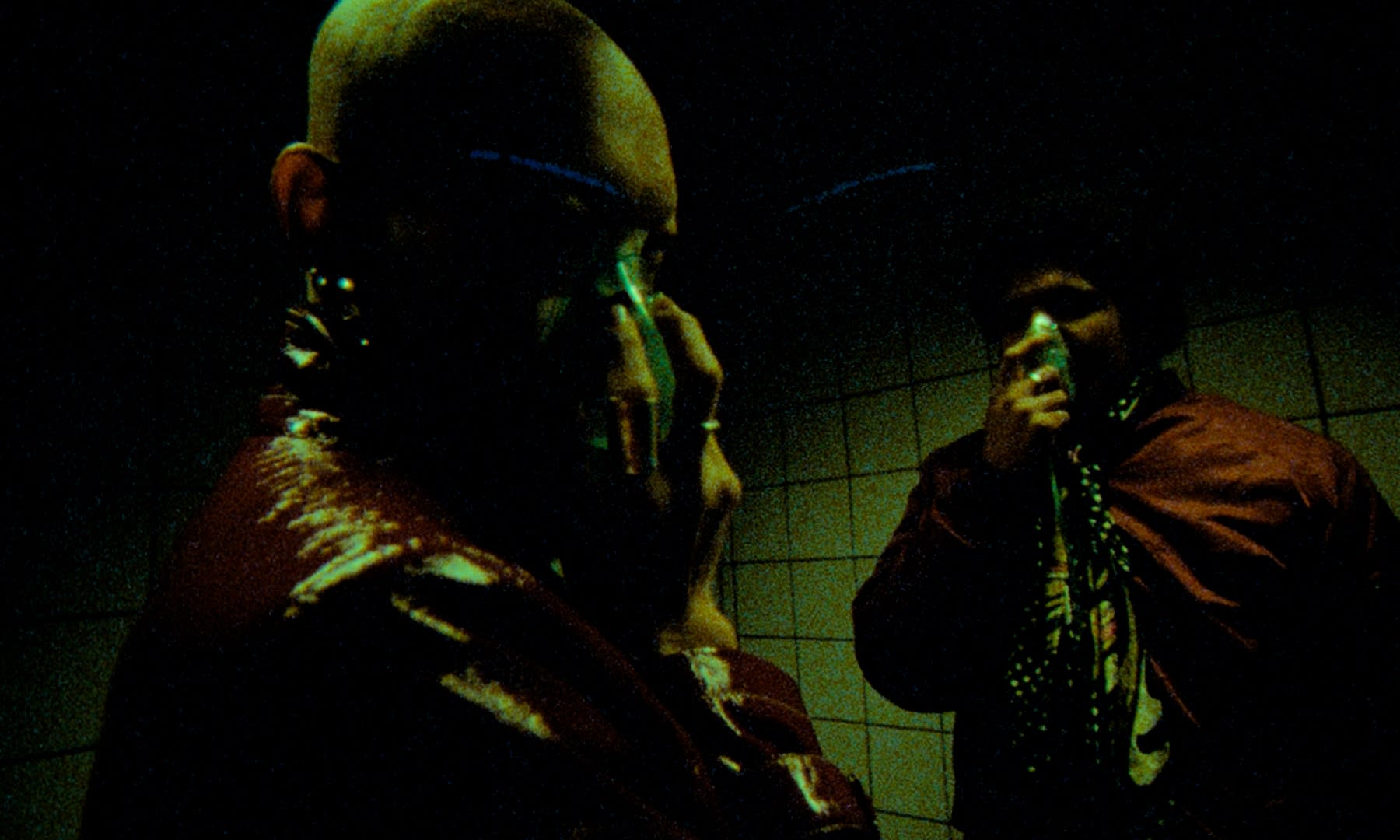 Dramatisches Color-Grading: Leuchtende Grün- und Rottöne in düsterer, urbaner Szene.