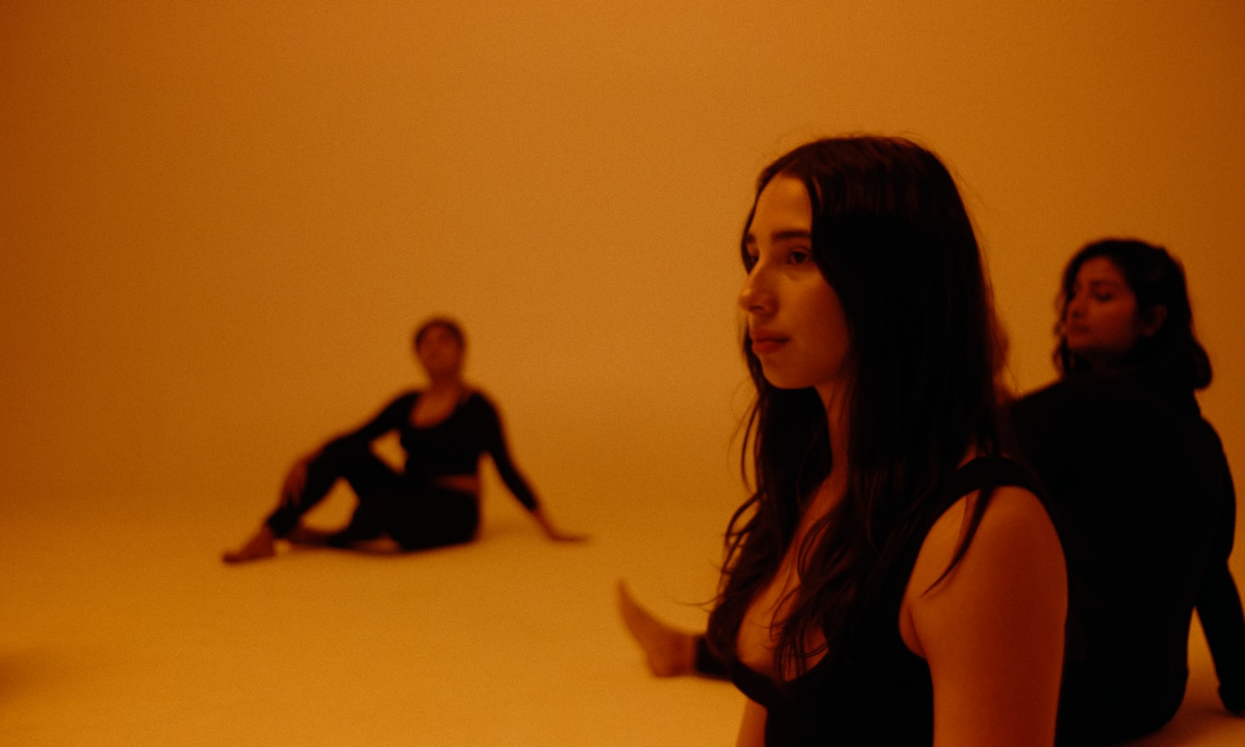 Künstlerisches Color-Grading taucht drei Frauen in warme, orangefarbene, meditative Töne.