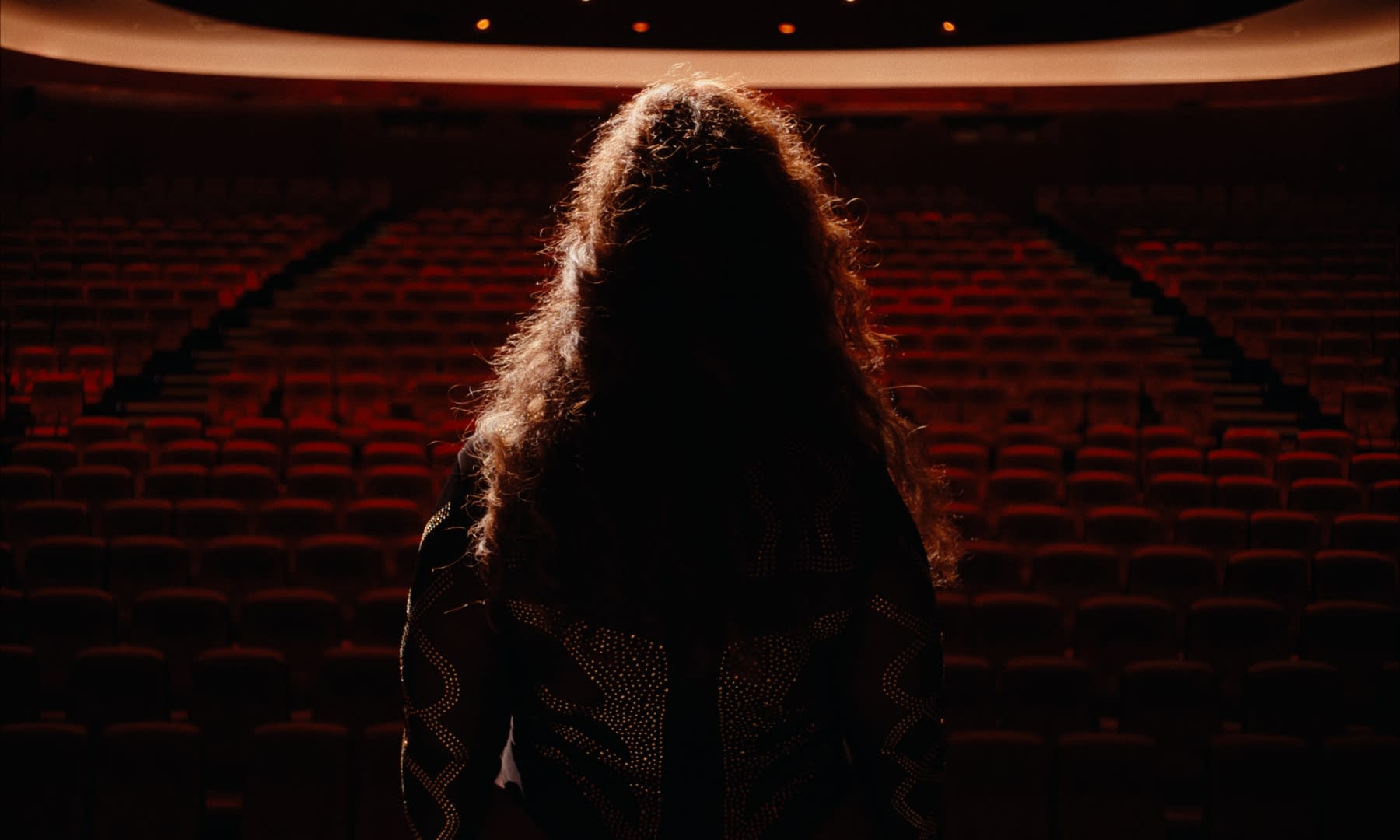 Dramatisches color-grading: Silhouette einer Frau vor rotem Theatersaal, intensive Stimmung.