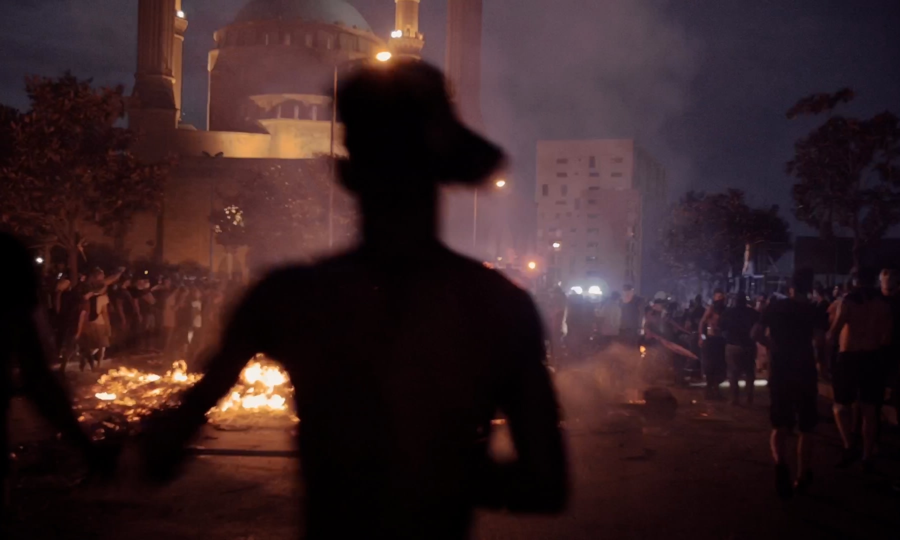 Nachtszene mit Feuern und Menschen. Meisterhaftes Grading verstärkt die dramatisch-chaotische Stimmung.