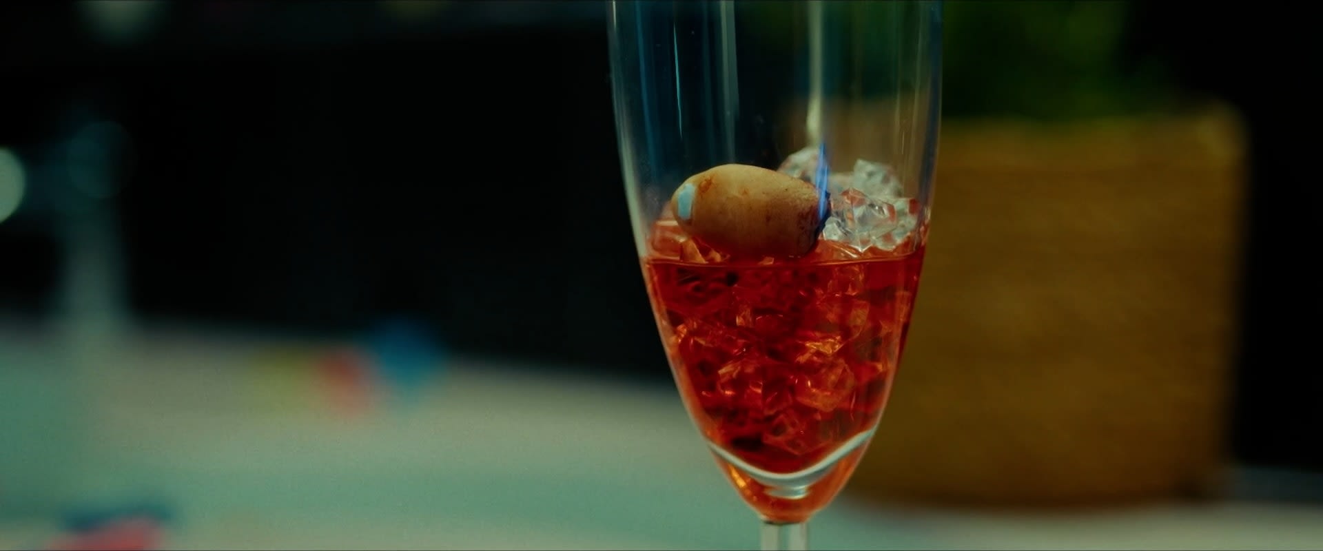 Intensives color-grading eines flammenden Cocktails: Rote Flüssigkeit, Eis, blaue Flamme in stimmungsvoller Nachtszene.