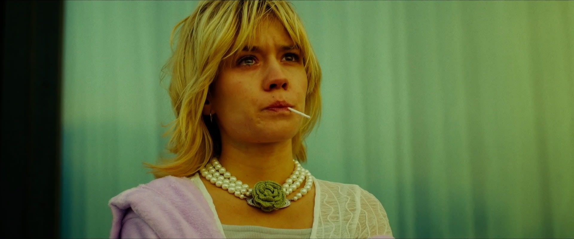 Colorist verleiht grünem Porträt mit Perlenkette stimmungsvolles Grading für emotionale Tiefe.