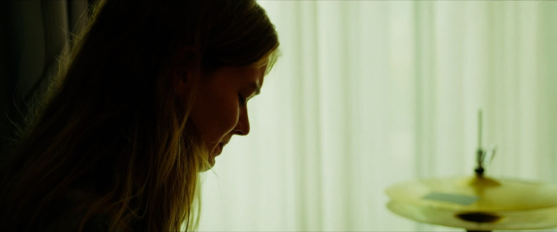 Stimmungsvolles Color-Grading: Frau im Profil, warmes Gegenlicht, ruhiger grüner Hintergrund.