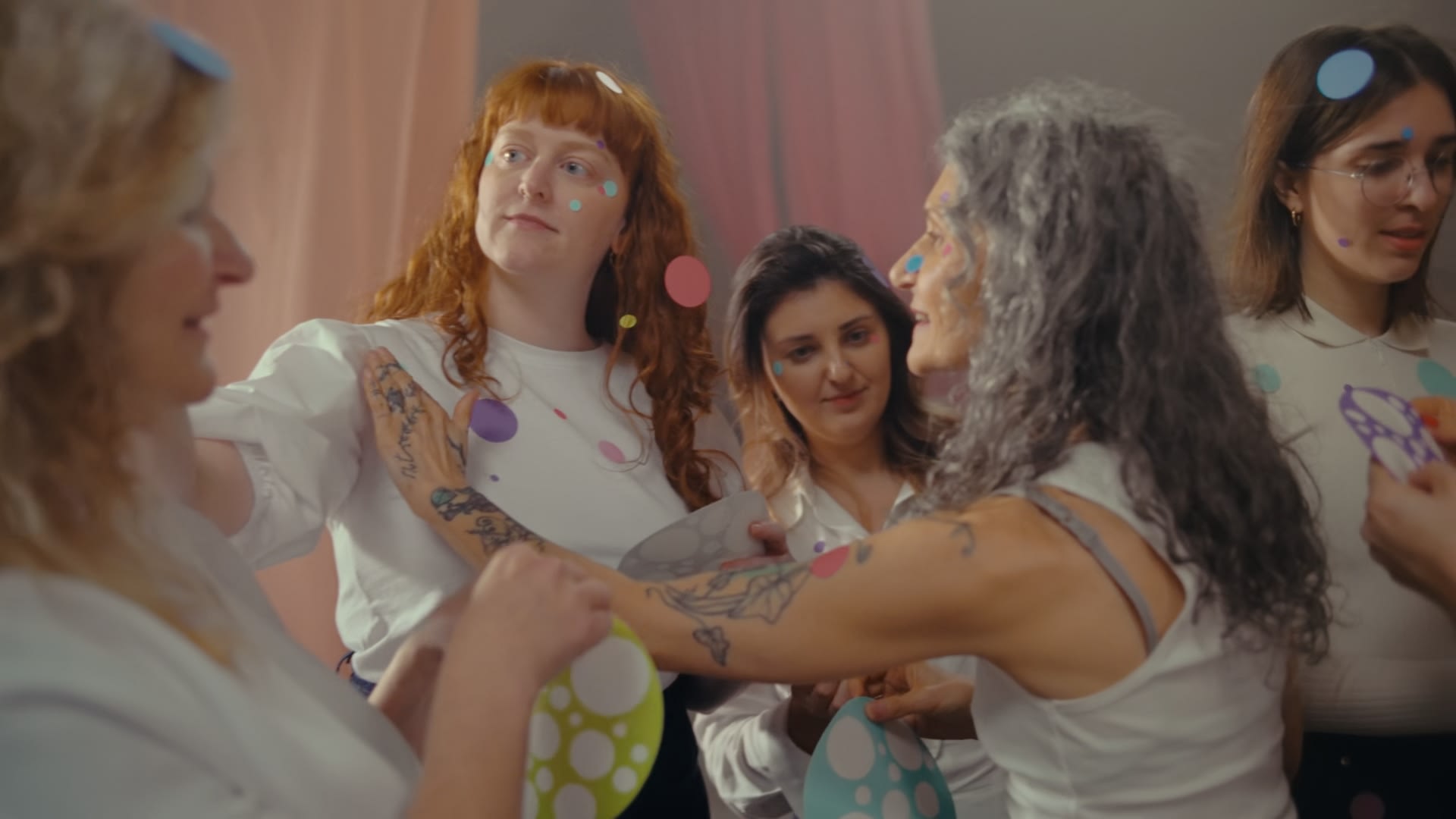 Warmes color-grading unterstreicht fröhliche Frauen mit Konfetti und Pastellfarben.