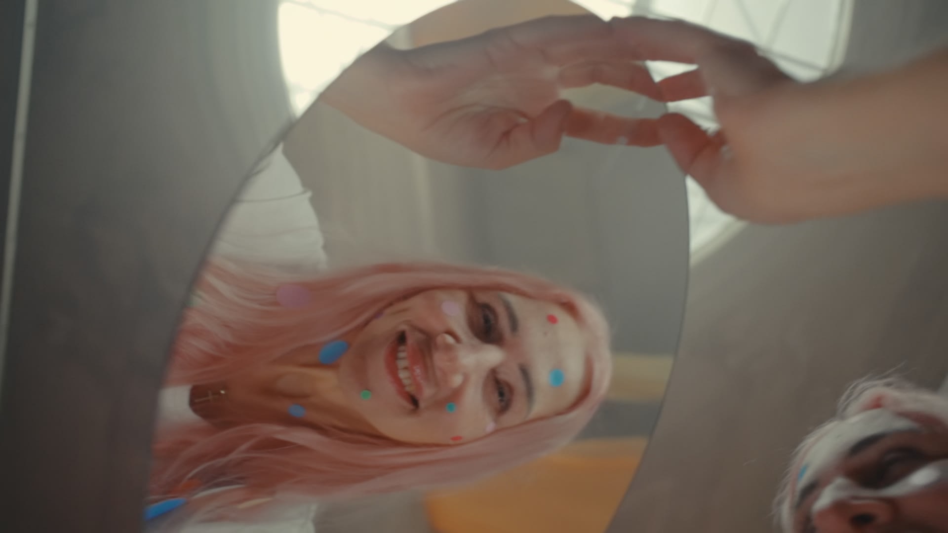 Fröhliche Frau mit pinken Haaren und Konfetti im Spiegel, meisterhaftes color-grading für lebendige Farben.