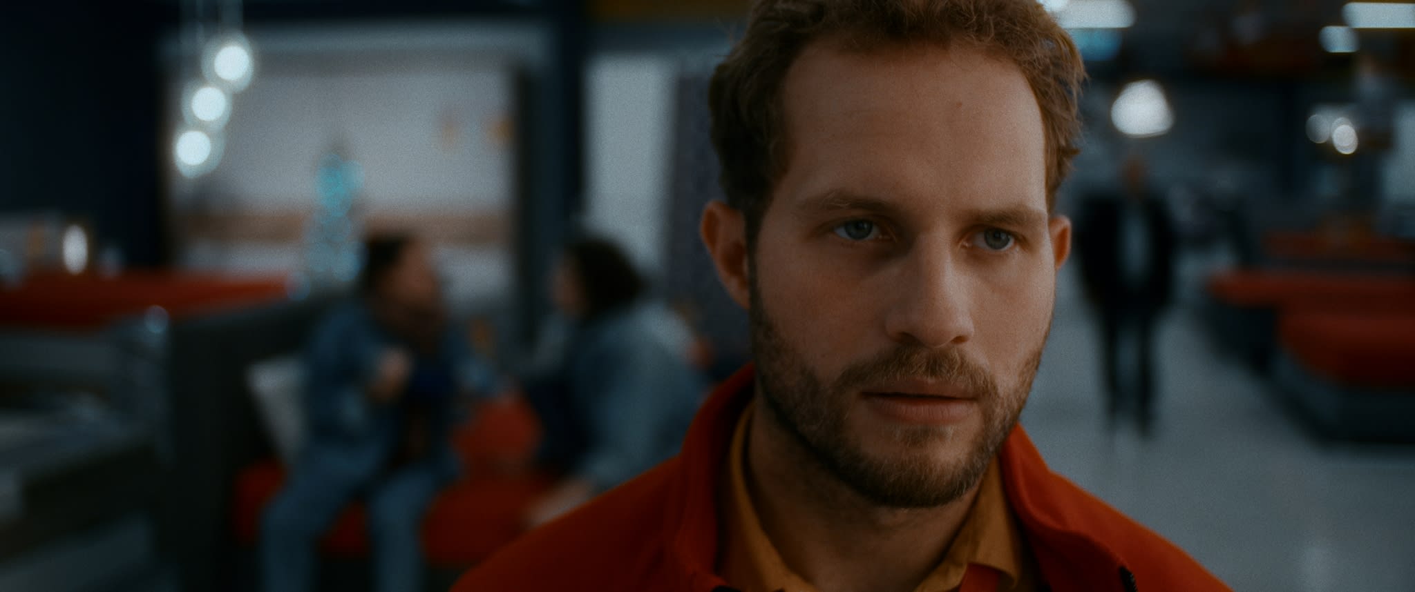 Nachdenklicher Mann in roter Jacke. Kinoästhetik durch meisterhaftes Color-Grading betont.