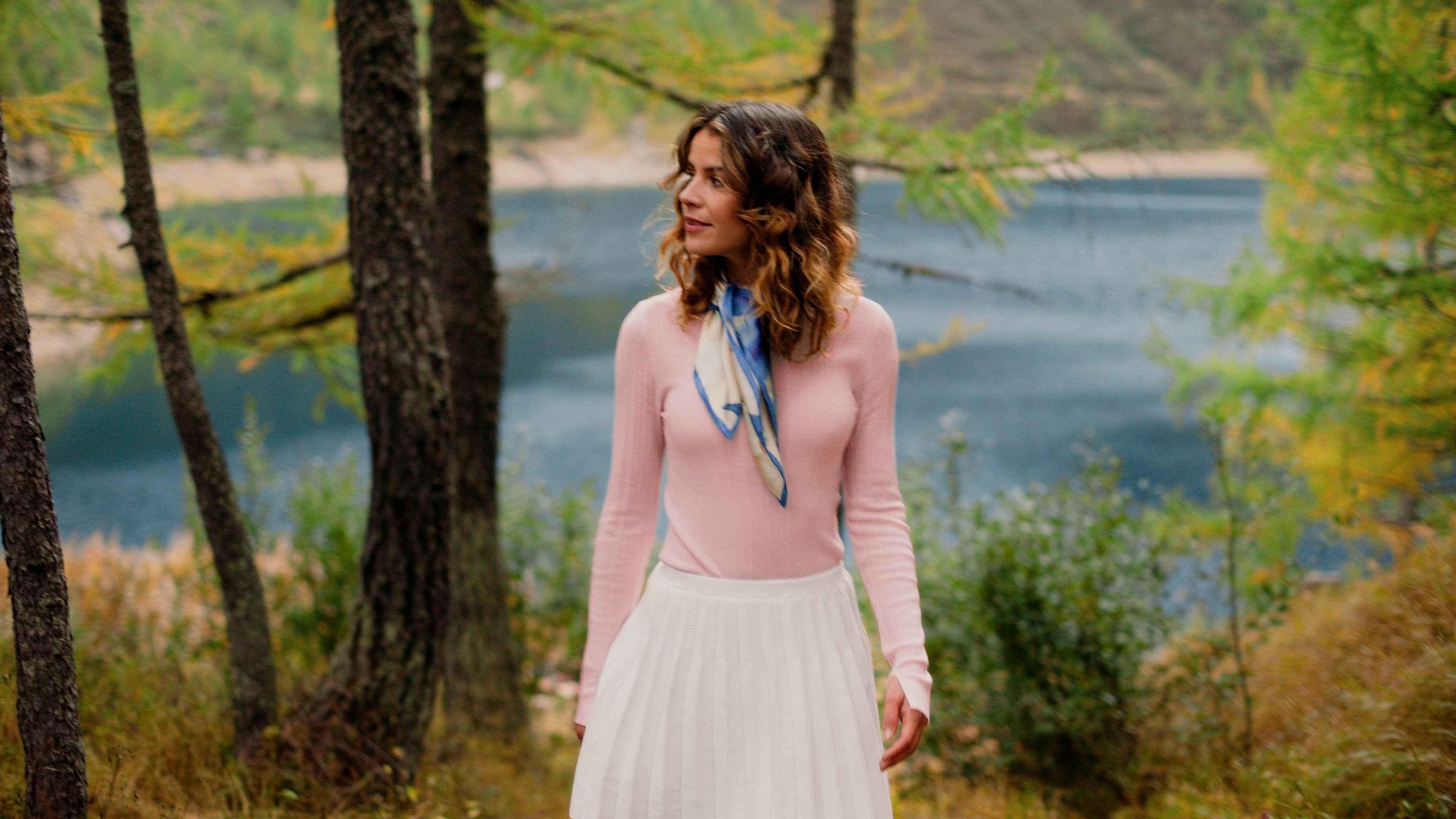 Elegante Frau in Pastelltönen am See. Professionelles colour-grading betont sanfte Herbstfarben und idyllische Stimmung.