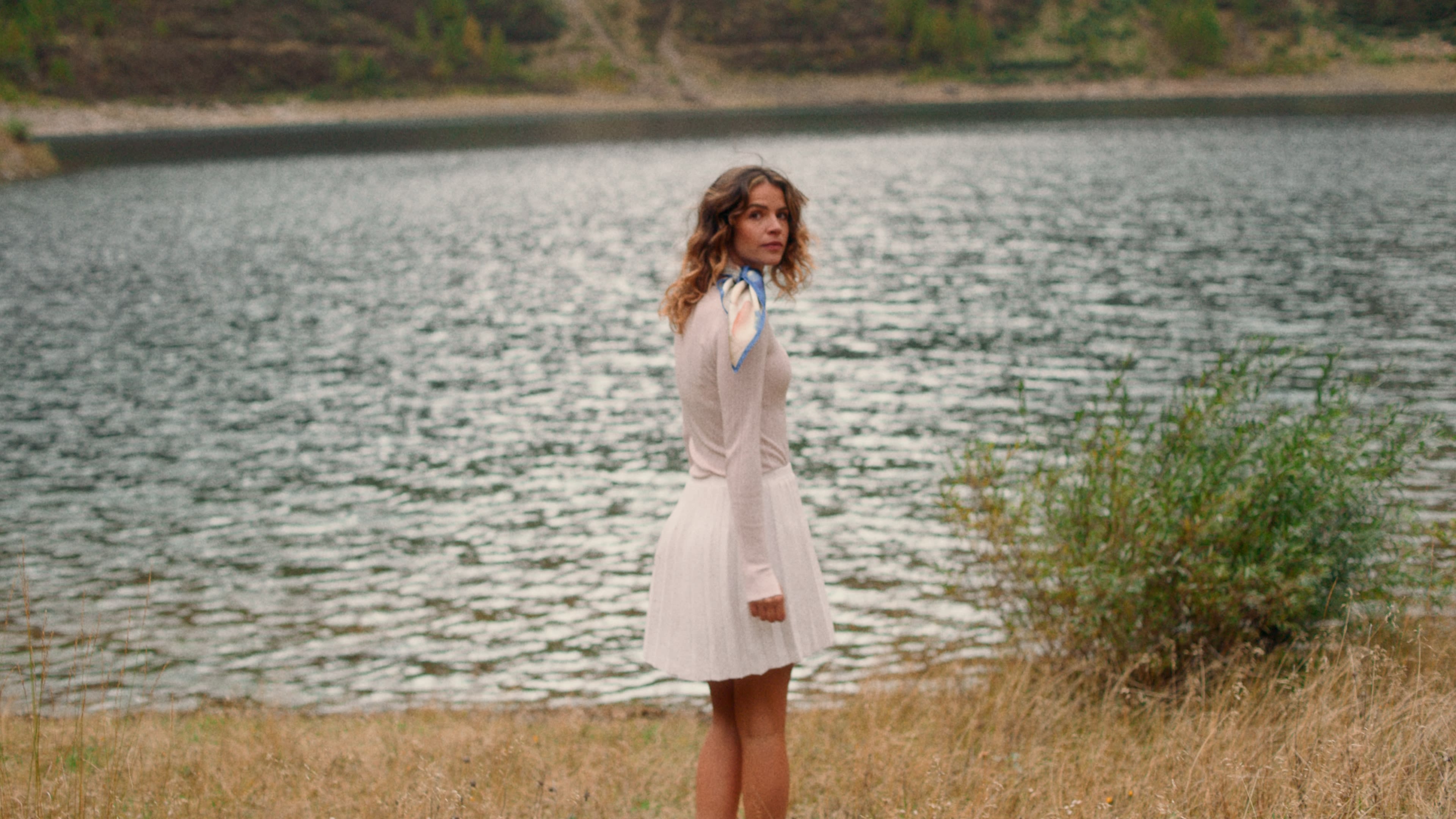 Junge Frau am Seeufer, warme Farben und stimmungsvolles Color Grading.