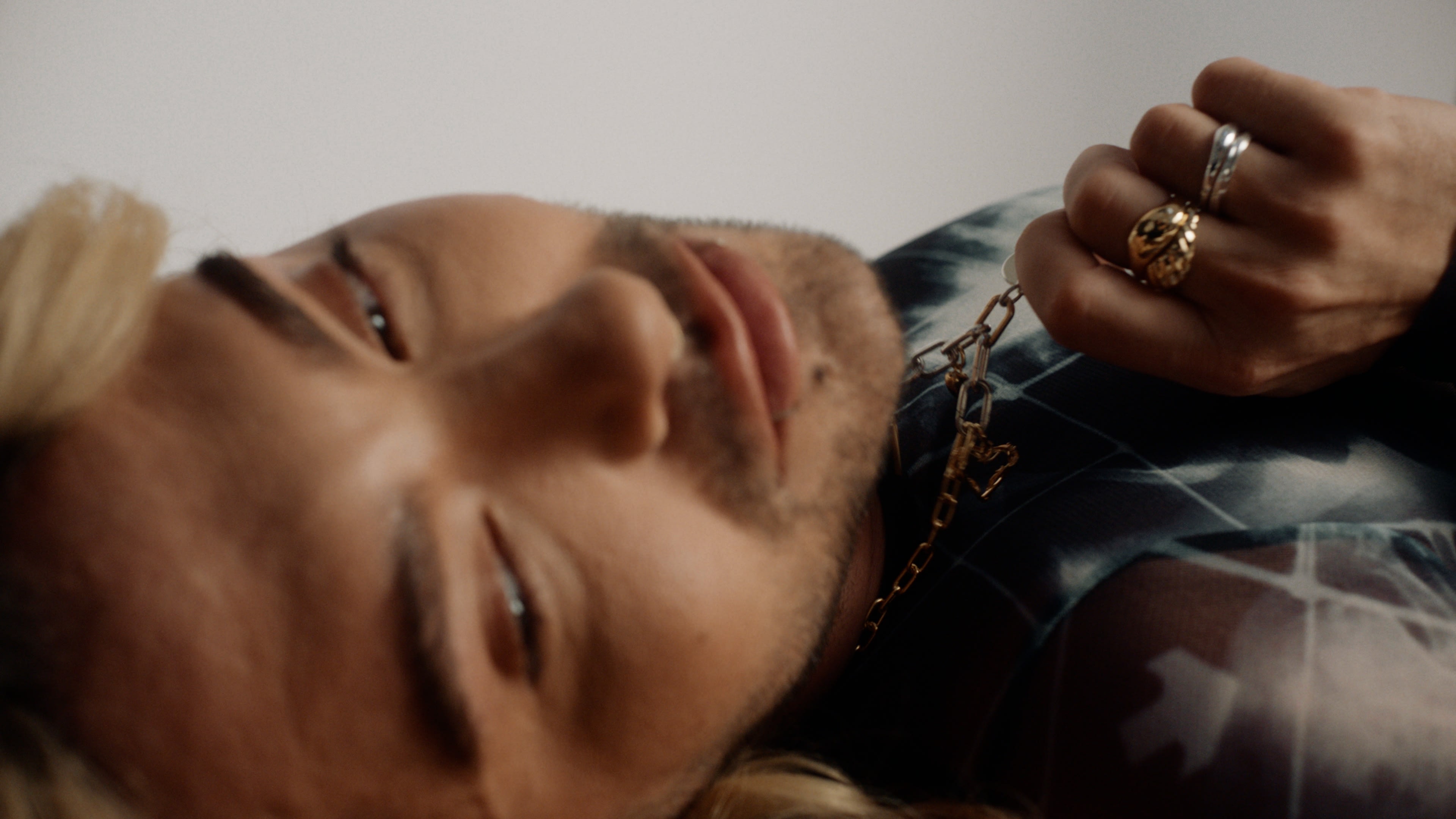 Nahaufnahme von Bill Kaulitz mit goldener Halskette und Ringen, Stimmungsvolles Color-Grading durch erfahrenen Coloristen.