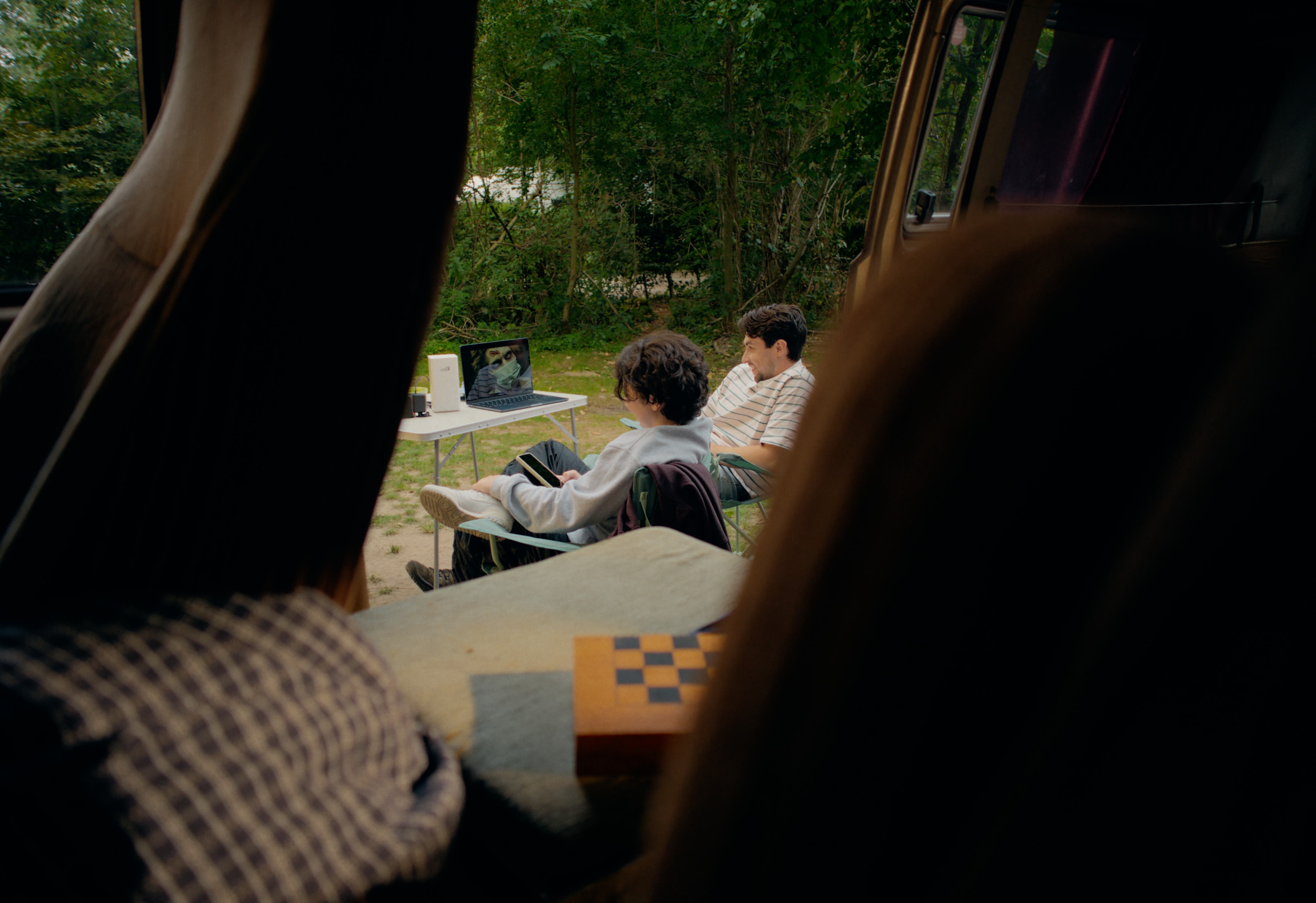 Zwei Männer beim Camping, natürlich mit warmem Color-Grading für entspannte Atmosphäre.