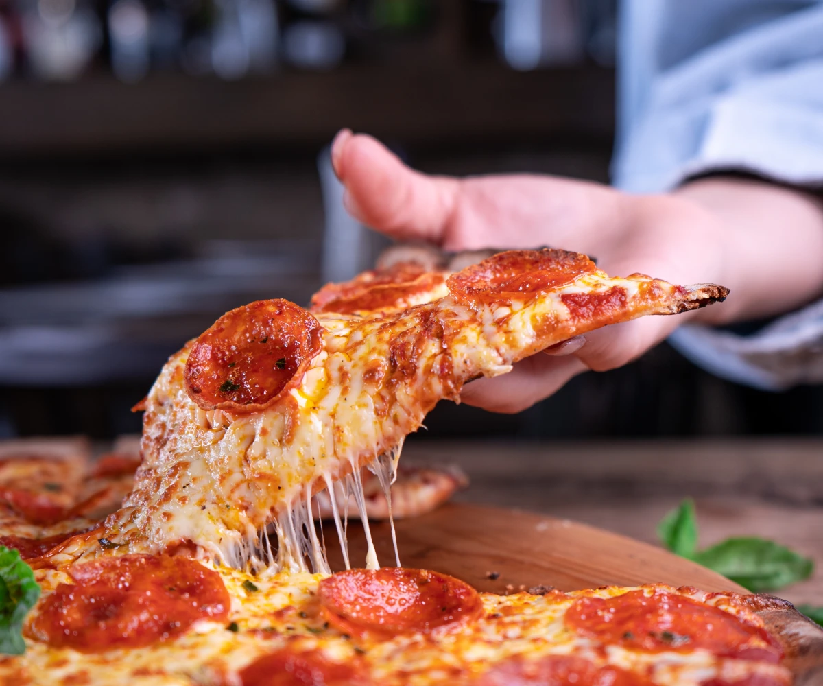 Women taking a piece of pizza from the table