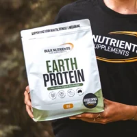 A customer holding a bag of earth protein smiles at the camera.