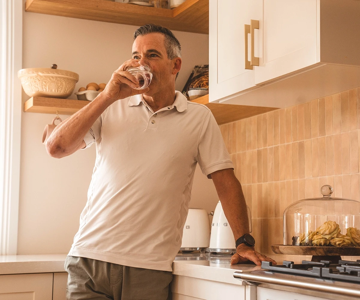 Man in the kitchen drinking a glass of water