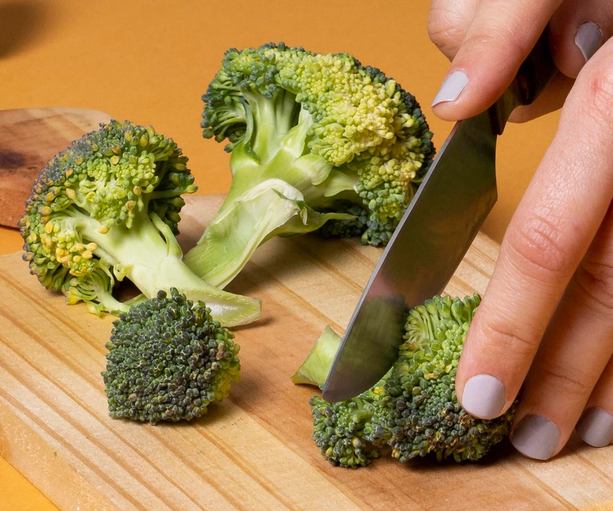 Fresh broccoli being cut on a cutting board table